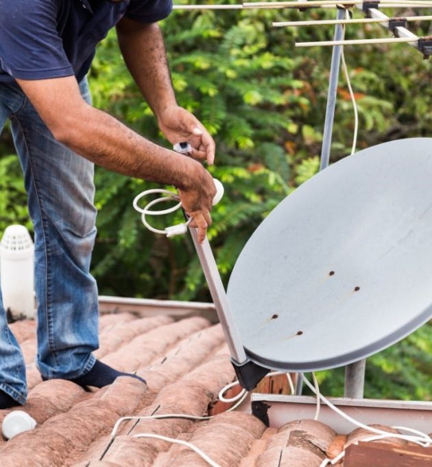 Installation d'une antenne parabolique sur un toit.